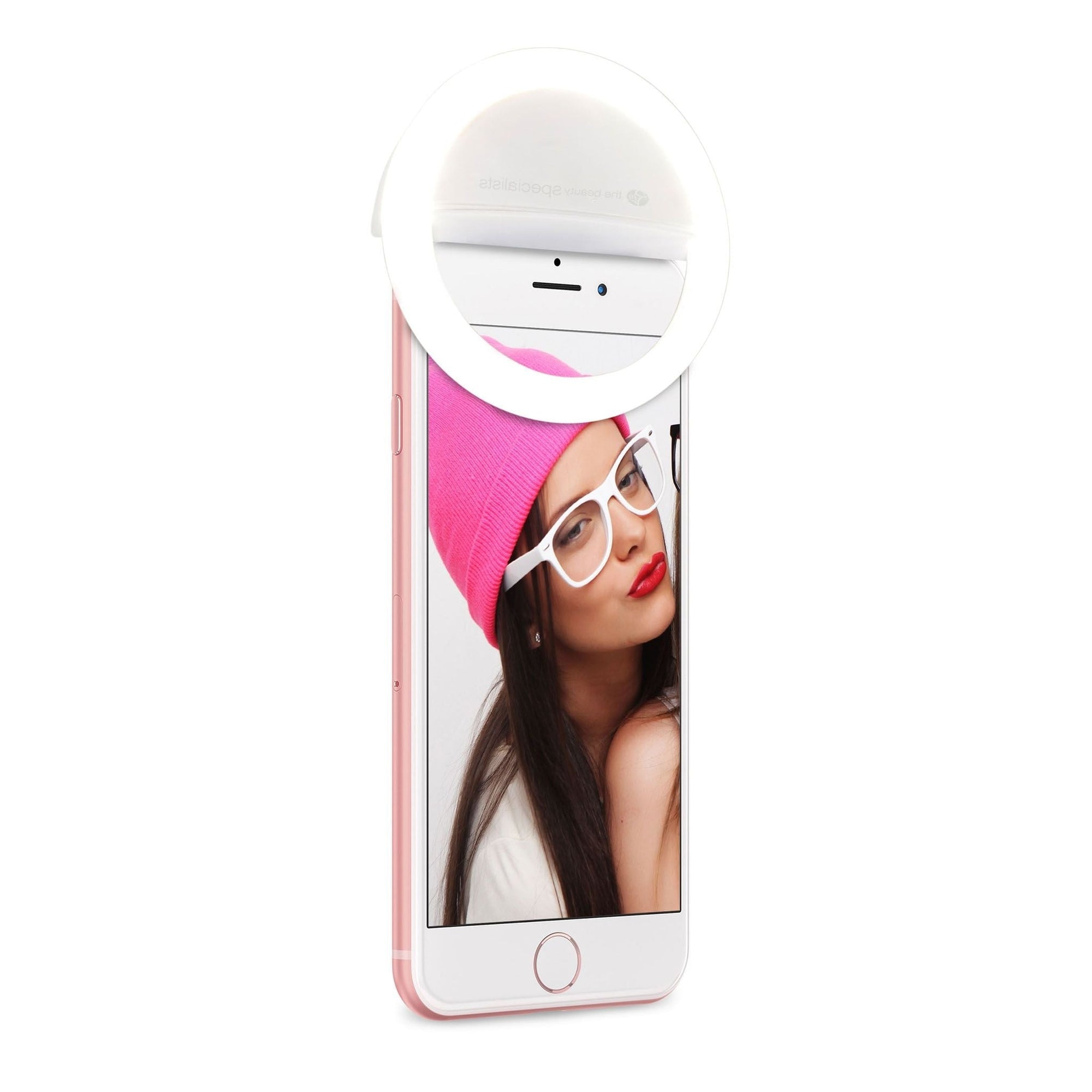 A woman in a pink beanie, white glasses, and red lipstick poses for a selfie using the Rio Beauty Glow Smartphone Ring Light attached to her phone.