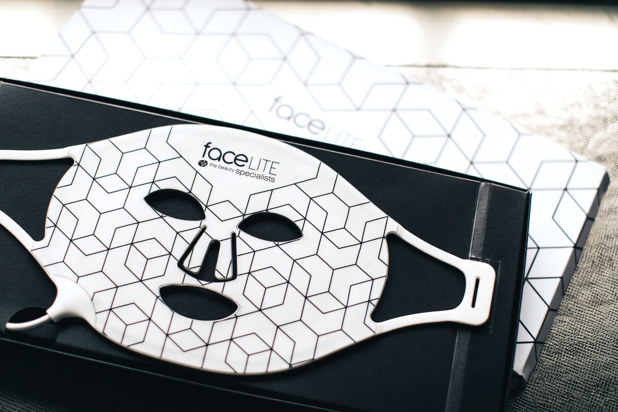 Facelite beauty boosting LED face mask laid flat in open product packaging 