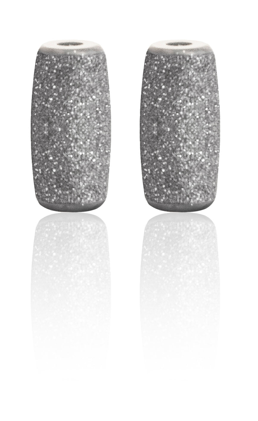 Two gray, cylindrical Replacement Roller Heads for the Rio 60 Second Pedi by Rio stand upright side by side, textured and sparkling, on a white reflective surface.