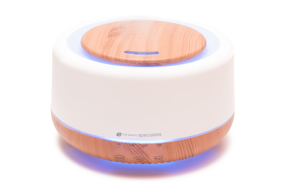 The Rio ALORA Aroma Diffuser, Humidifier &amp; Night-Light features a round white body with light wood accents, control buttons, and a glowing blue base for ambiance.
